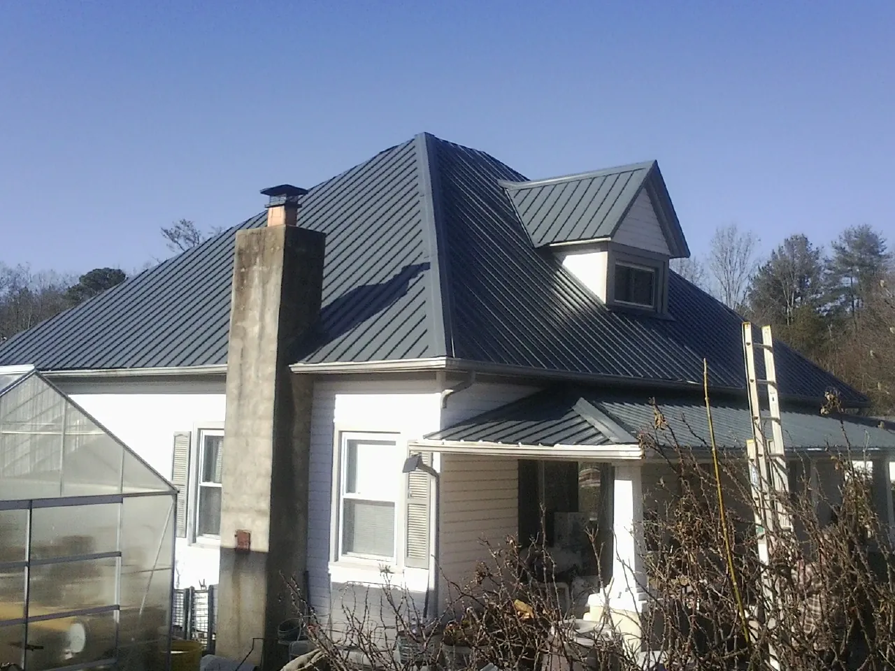 Dark blue standing seam metal roof on a white farmhouse with dormer — Slate & Tile Roof Repair by Roofing Brothers in Adah