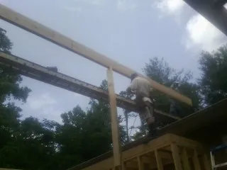 Carpenter setting a ridge beam over a new addition frame — Ice Dam Removal by Roofing Brothers in Adah