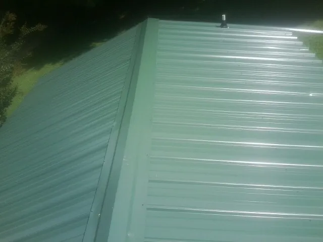 New green metal panels meeting at the ridge of a roof — Flat Roof Repair work by our crew in Adah