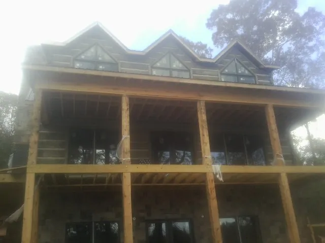 Dormers and porch framing on a large log home under construction — Roof Coating work by our crew in Adah