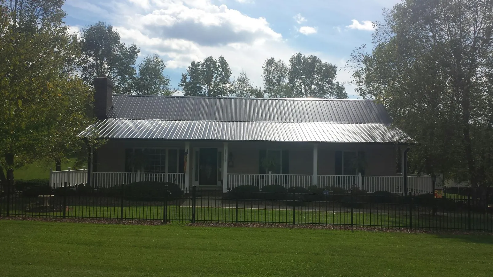 Gray metal roof on a brick ranch with a full width front porch — Gutter Guard Installation work by our crew in Adah
