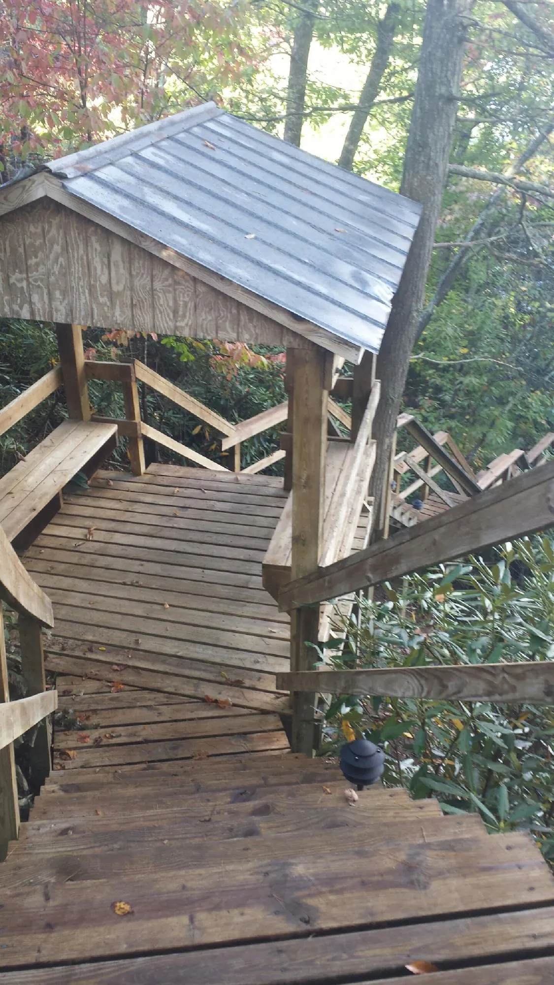 Metal roofed shelter over wooden steps on a wooded walkway — Skylight Repair & Installation work by our crew in Adah