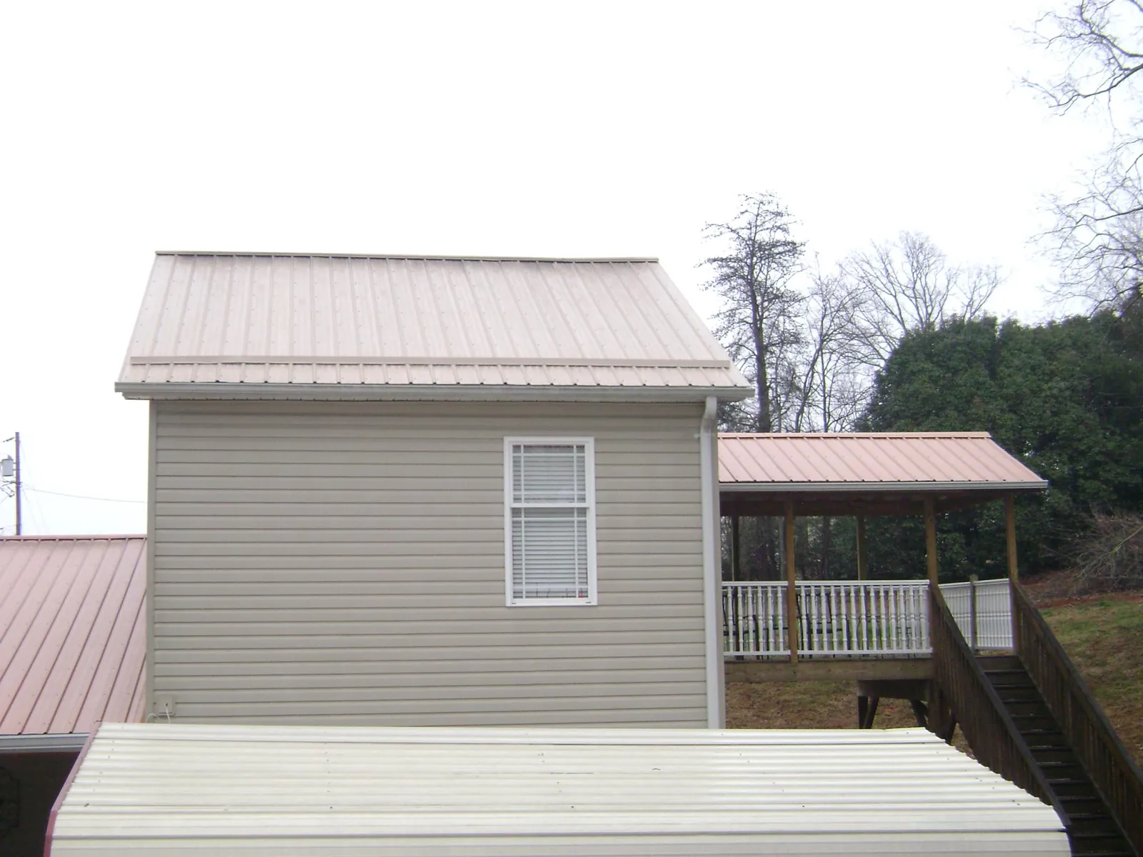 Tan metal roofs on a two story addition and attached porch, from a Roof Replacement job in Adah