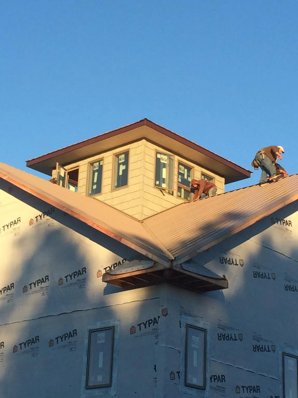 Roofers working around a rooftop cupola on a new metal roof at sunset — Roof Waterproofing in Adah by Roofing Brothers